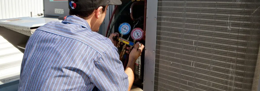 HVAC technician servicing a condenser unit in Ellington